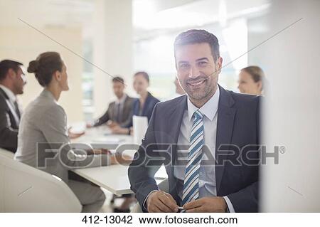 Stock Image - Portrait of confident businessman in conference room. Fotosearch