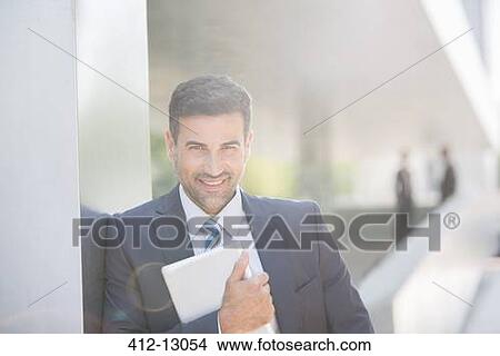 Picture - Portrait of confident businessman holding digital tablet outdoors. Fotosearch