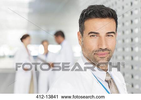 Portrait of confident doctor in hospital corridor View Large Photo Image Stock Image - Portrait of confident doctor in hospital corridor. Fotosearch