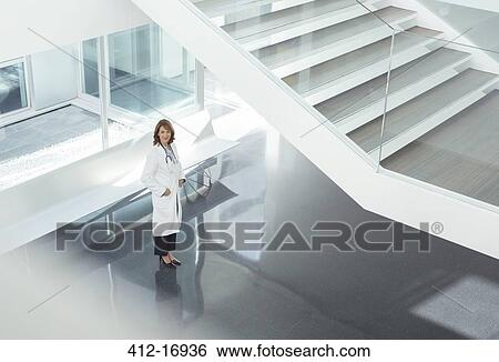 Portrait of confident doctor in hospital lobby View Large Photo Image Stock Photograph - Portrait of confident doctor in hospital lobby. Fotosearch