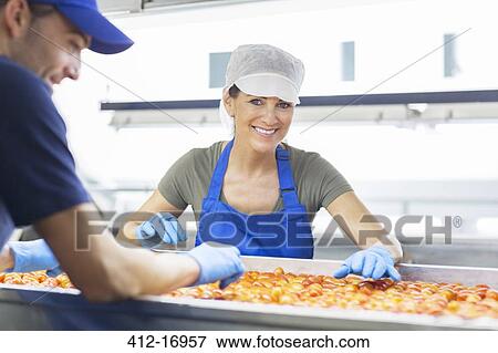 Stock Photo - Portrait of confident worker examining tomatoes in food processing plant. Fotosearch