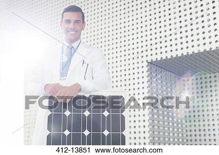 Stock Image - Portrait of scientist with solar panel in laboratory. Fotosearch