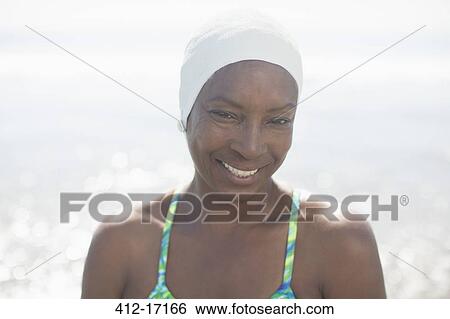 Stock Photograph - Portrait of smiling woman in swimming cap at beach. Fotosearch