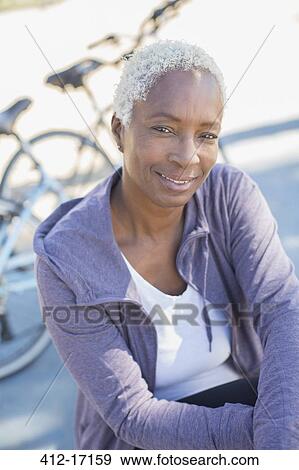 Stock Photo - Portrait of smiling woman near bicycle. Fotosearch