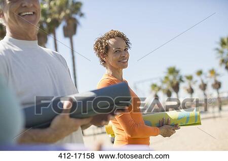 Portrait of smiling woman with yoga mat at beach View Large Photo Image Stock Photo - Portrait of smiling woman with yoga mat at beach. Fotosearch