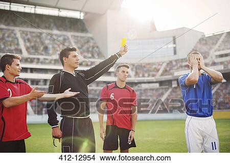 Picture - Referee flashing yellow card at soccer player on field. Fotosearch