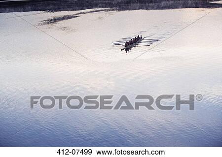 Rowing crew rowing scull on lake in distance View Large Photo Image Stock Photo - Rowing crew rowing scull on lake in distance. Fotosearch