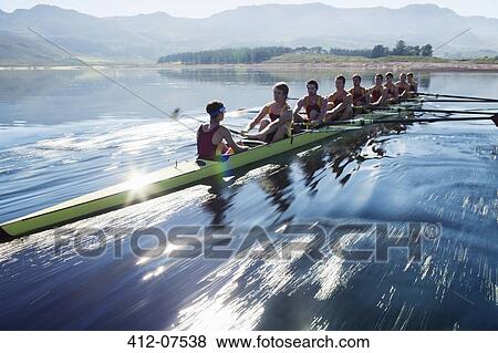 Stock Photo - Rowing team rowing scull on lake. Fotosearch