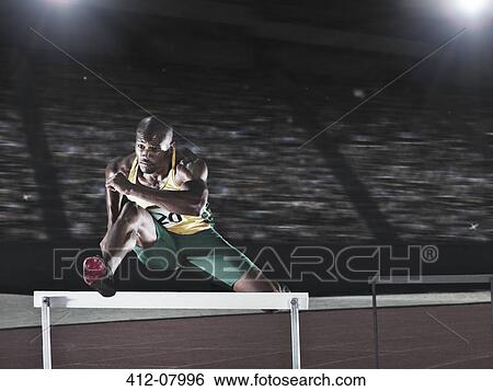 Runner jumping hurdle on track View Large Photo Image Stock Photograph - Runner jumping hurdle on track. Fotosearch