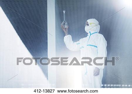 Stock Photo - Scientist in clean suit examining liquid in beaker. Fotosearch