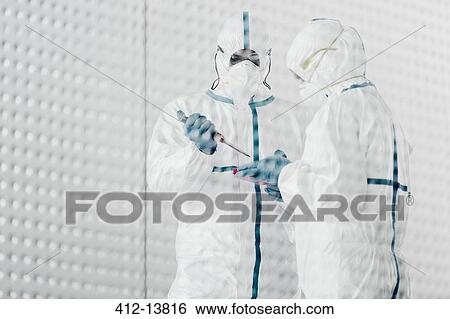 Stock Photograph - Scientists in clean suits working in laboratory. Fotosearch