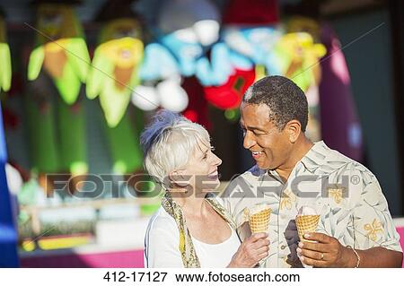 Senior couple eating ice cream cones at amusement park View Large Photo Image Stock Photo - Senior couple eating ice cream cones at amusement park. Fotosearch