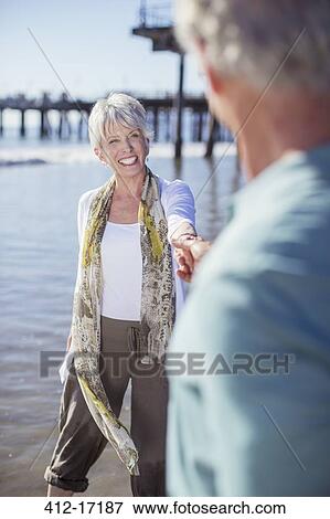Stock Photo - Senior couple holding hands on beach. Fotosearch