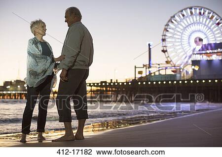 Stock Image - Senior couple on beach at night. Fotosearch