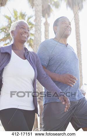 Stock Image - Senior couple power walking outdoors. Fotosearch