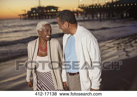 Senior couple walking on beach at sunset View Large Photo Image Stock Photo - Senior couple walking on beach at sunset. Fotosearch