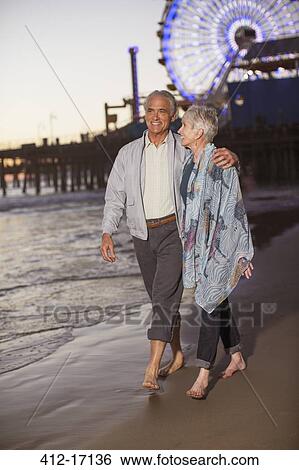 Senior couple walking on beach at sunset View Large Photo Image Stock Photograph - Senior couple walking on beach at sunset. Fotosearch