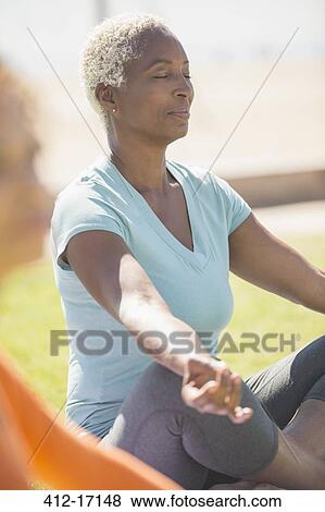 Serene woman meditating in lotus position outdoors View Large Photo Image Stock Photo - Serene woman meditating in lotus position outdoors. Fotosearch