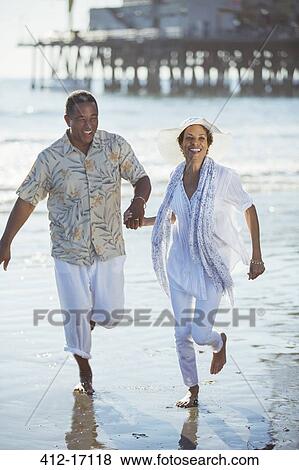 Smiling senior couple running on sunny beach View Large Photo Image Stock Photo - Smiling senior couple running on sunny beach. Fotosearch