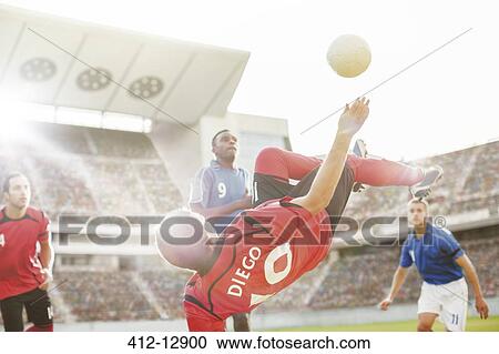 Stock Image - Soccer player kicking ball on field. Fotosearch