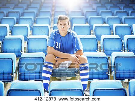 Stock Photo - Soccer player sitting in empty stadium. Fotosearch
