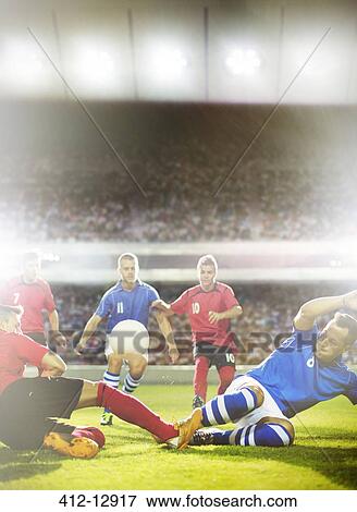 Soccer players kicking at ball on field View Large Photo Image Stock Photo - Soccer players kicking at ball on field. Fotosearch