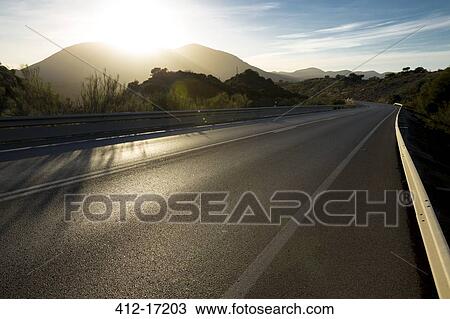 Sun shining over mountains and open road View Large Photo Image Stock Image - Sun shining over mountains and open road. Fotosearch