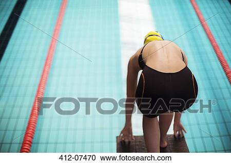 Swimmer poised at starting block above pool View Large Photo Image Stock Image - Swimmer poised at starting block above pool. Fotosearch