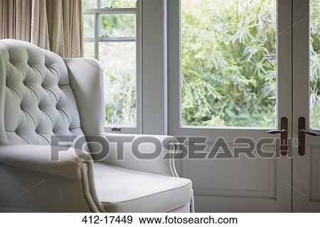 Stock Photo - Tufted wingback chair near window. Fotosearch