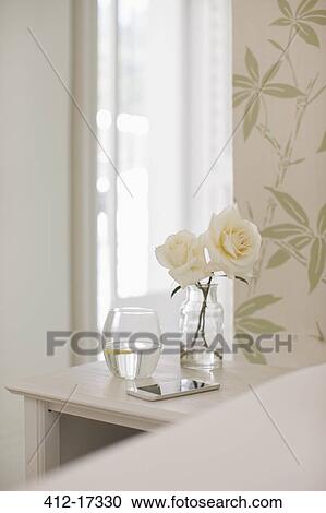 Stock Image - White roses on bedside table. Fotosearch