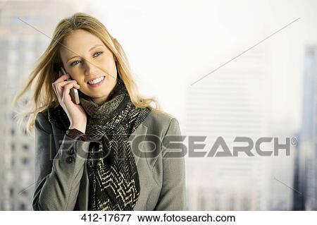 Stock Photo - Businesswoman talking on cell phone in urban window. Fotosearch