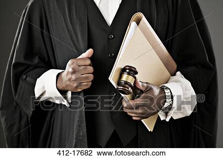 Stock Image - Close up of judge holding file and gavel. Fotosearch
