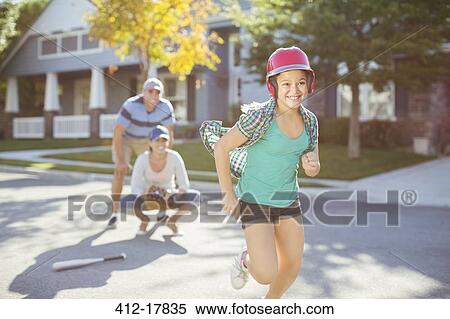 Stock Photography - Family playing baseball in street. Fotosearch