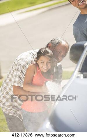 Stock Photograph - Grandfather and granddaughter washing car in driveway. Fotosearch