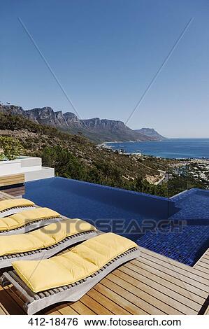 Stock Photograph - Lounge chairs at poolside overlooking ocean. Fotosearch