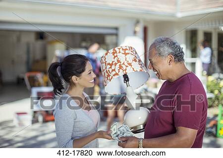 Stock Image - Man buying lamp at yard sale. Fotosearch