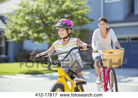 Mother and daughter riding bicycles in sunny street View Large Photo Image Stock Photo - Mother and daughter riding bicycles in sunny street. Fotosearch