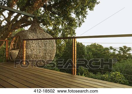 Stock Image - Nest tree house beyond wood deck. Fotosearch
