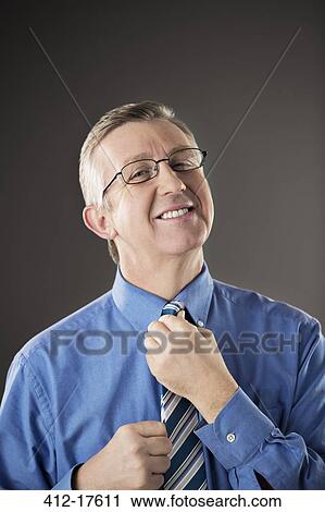 Portrait of businessman adjusting his tie View Large Photo Image Stock Image - Portrait of businessman adjusting his tie. Fotosearch