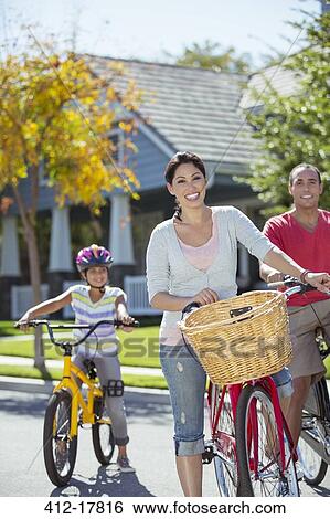 Stock Photograph - Portrait of happy family with bicycles in street. Fotosearch