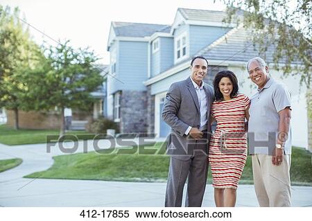 Stock Photography - Portrait of smiling family in driveway. Fotosearch