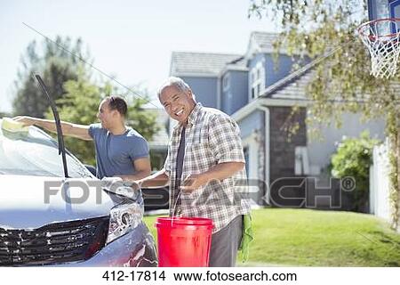 Portrait of smiling father and son washing car in driveway View Large Photo Image Picture - Portrait of smiling father and son washing car in driveway. Fotosearch