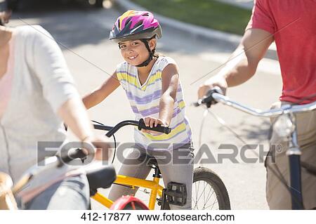 Portrait of smiling girl riding bicycle with parents View Large Photo Image Stock Photo - Portrait of smiling girl riding bicycle with parents. Fotosearch