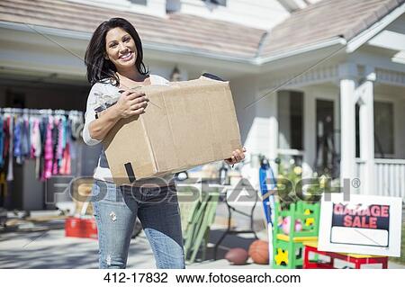 Portrait of smiling woman with box at yard sale View Large Photo Image Stock Image - Portrait of smiling woman with box at yard sale. Fotosearch
