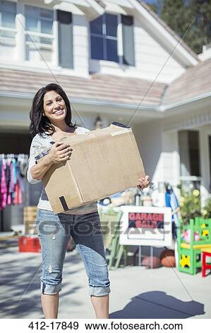 Portrait of smiling woman with box at garage sale View Large Photo Image Stock Photo - Portrait of smiling woman with box at garage sale. Fotosearch