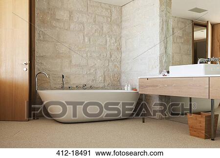 Stone wall behind soaking tub in modern bathroom View Large Photo Image Stock Image - Stone wall behind soaking tub in modern bathroom. Fotosearch