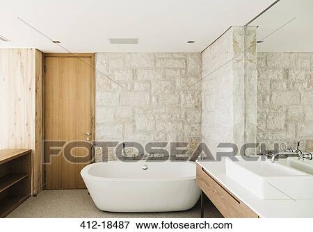 Stone walls behind soaking tub in modern bathroom View Large Photo Image Stock Photo - Stone walls behind soaking tub in modern bathroom. Fotosearch