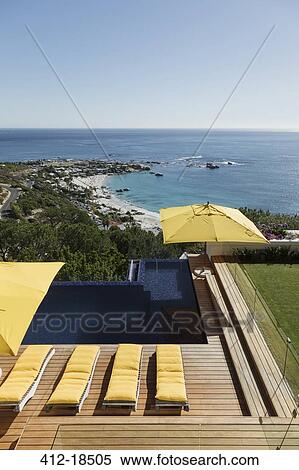 Stock Photography - View of ocean beyond luxury swimming pool and patio. Fotosearch