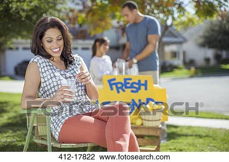 Stock Image - Woman drinking lemonade at lemonade stand. Fotosearch