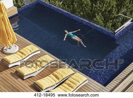 Woman floating in luxury swimming pool View Large Photo Image Stock Photography - Woman floating in luxury swimming pool. Fotosearch